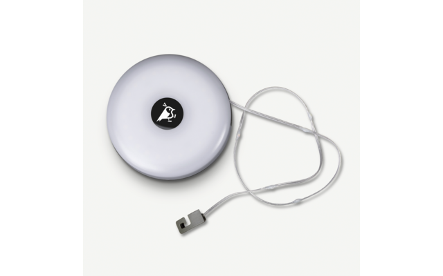 Rundes weißes Gehäuse mit schwarzem Kreis und weißem Symbol in der Mitte, aufgerolltes transparentes Band mit Metallhaken neben dem Gehäuse, heller Hintergrund