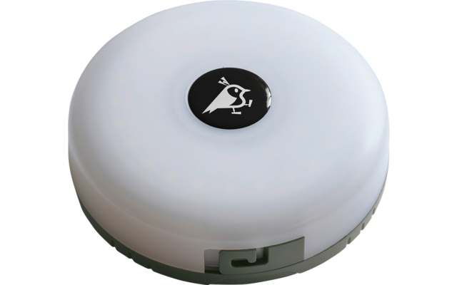 Rundes, flaches weißes Kunststoffgehäuse mit Schatten; mittig schwarzer runder Knopf mit weißem Piktogramm einer stilisierten Person; seitlicher grüner Rand mit Ausschnitt