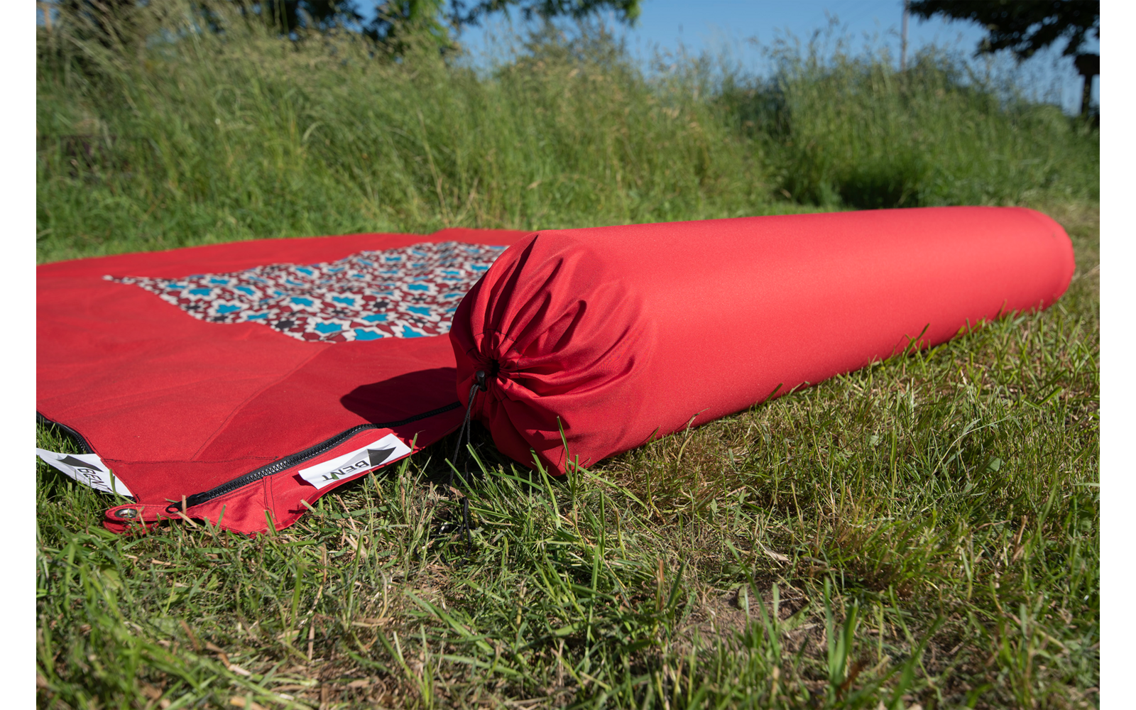 Rote zusammengerollte Yogamatte liegt auf Gras