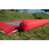 Red rolled-up yoga mat lying on grass