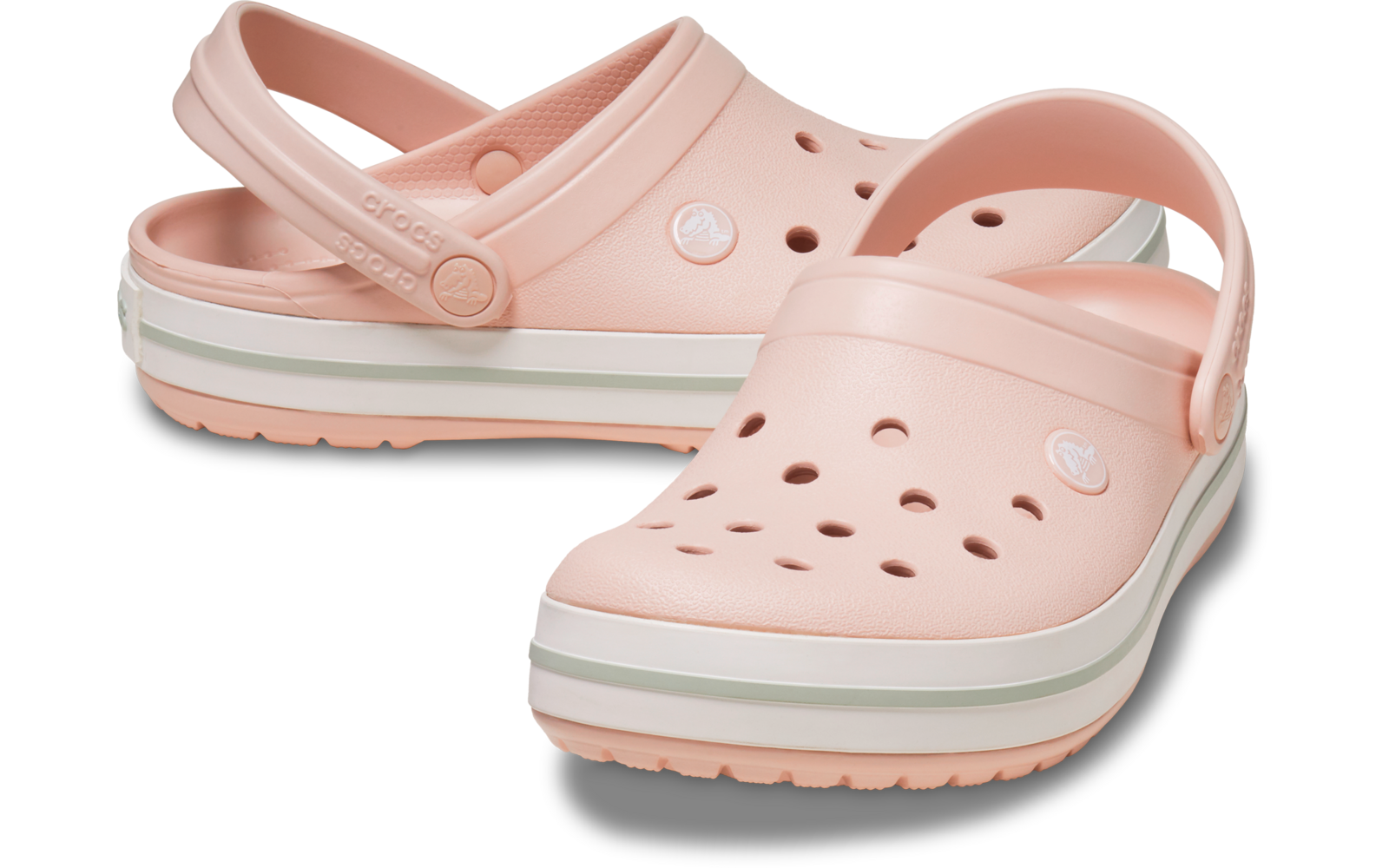 Zwei hellrosa Kunststoff‑Clogs mit Fersenriemen und Löchern, weiße Sohle mit grünem Streifen