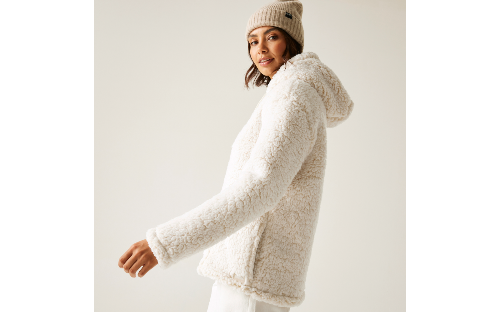 Frau trägt eine weiße, flauschige Kapuzenjacke und eine beige Mütze