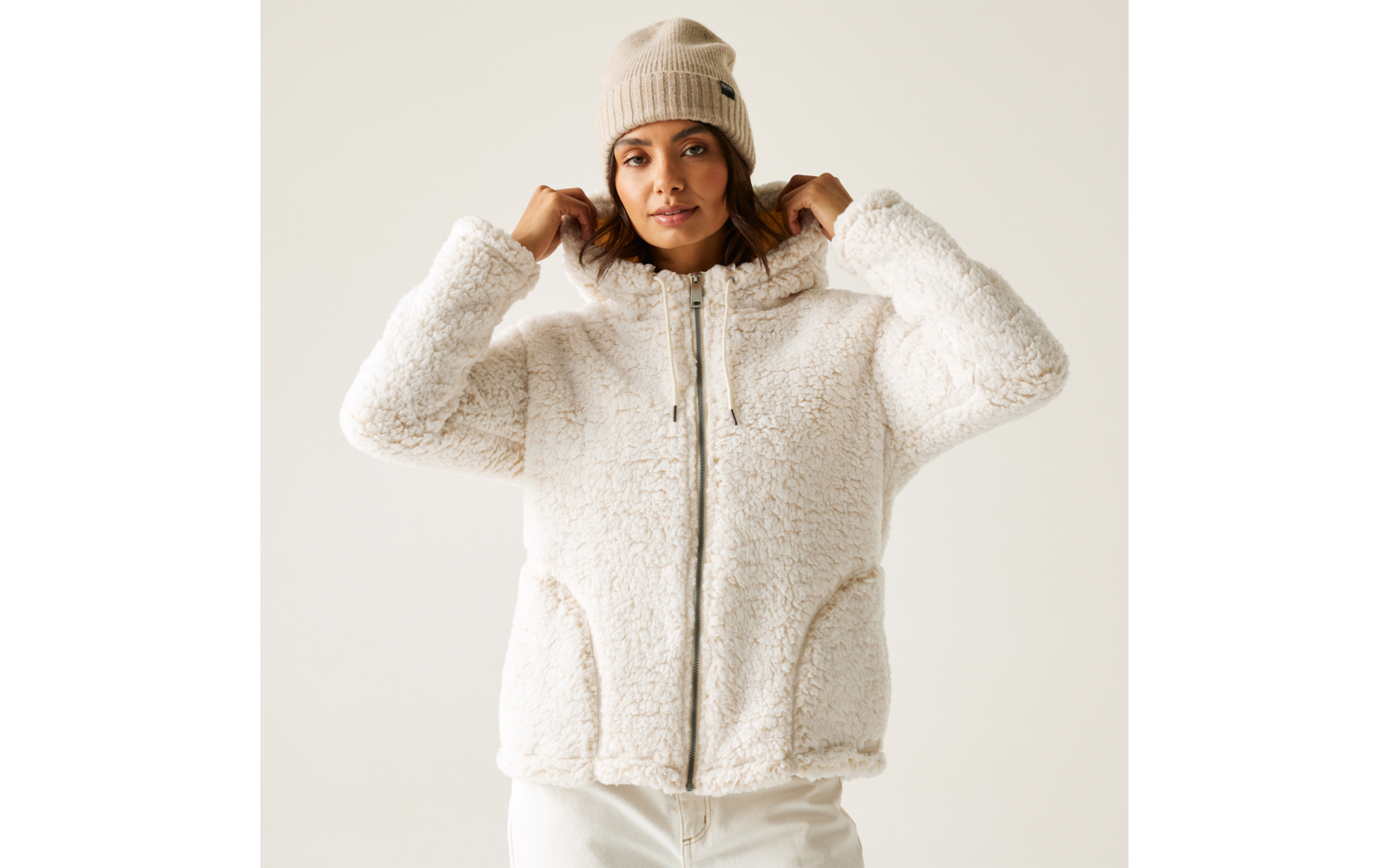 Frau trägt eine weiße, flauschige Jacke und eine beige Mütze