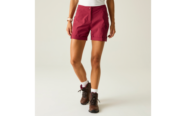 Unterkörper einer stehenden Person mit bordeauxroten Shorts, weißem Oberteilsaum, weißen Socken und braunen knöchelhohen Schuhen vor hellem Hintergrund