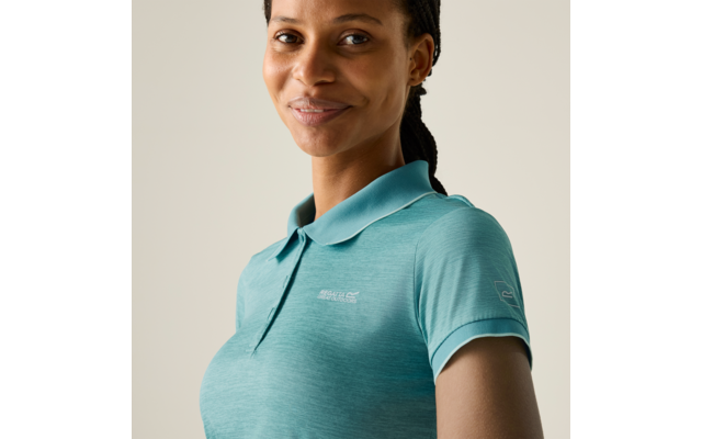 Person, Brustansicht, leichter Lächeln, trägt türkisfarbenes Poloshirt mit kleinen Logos auf Brust und Ärmel, Zöpfe nach hinten gelegt, einfarbiger heller Hintergrund