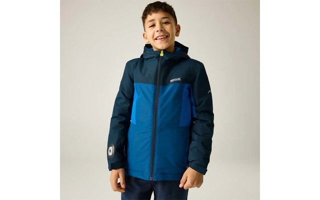 Garçon souriant aux cheveux bruns courts portant une veste à capuche bleu bicolore, debout devant un fond uni clair