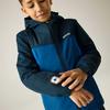 Un garçon en veste à capuche bleue touche une lampe ronde sur son avant-bras gauche