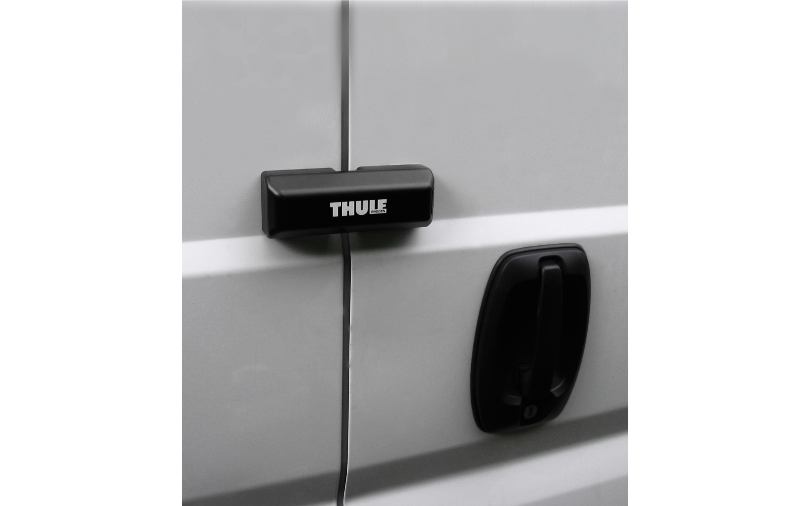 Porta di veicolo grigio chiaro con giunzione della porta, pezzo rettangolare nero con la scritta 'THULE' che attraversa la giunzione, maniglia della porta nera a destra