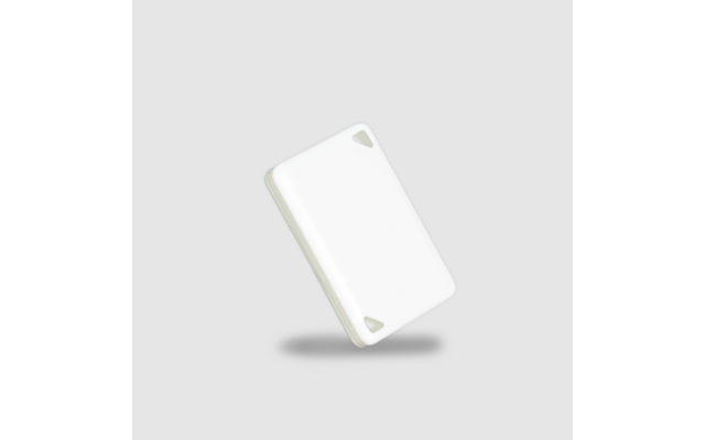 Weißes rechteckiges Kunststoffplättchen mit abgerundeten Ecken und zwei dreieckigen Aussparungen in den Ecken, schräg angeordnet, Schatten auf hellgrauem Hintergrund