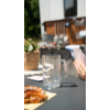 Glas, Kaffeetasse und Croissant auf einem Tisch, im Hintergrund Küchenregal mit Geschirr