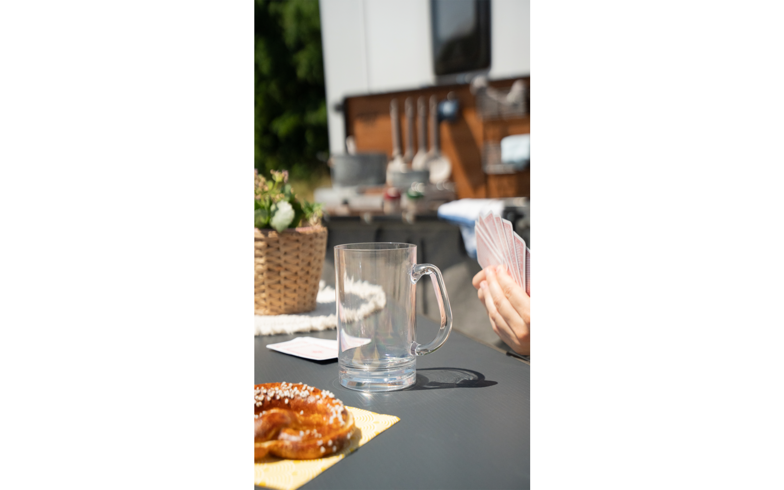 Glas, Kaffeetasse und Croissant auf einem Tisch, im Hintergrund Küchenregal mit Geschirr