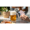 Glas Bier mit Schaum, Hände halten Spielkarten, Brezel auf Tisch