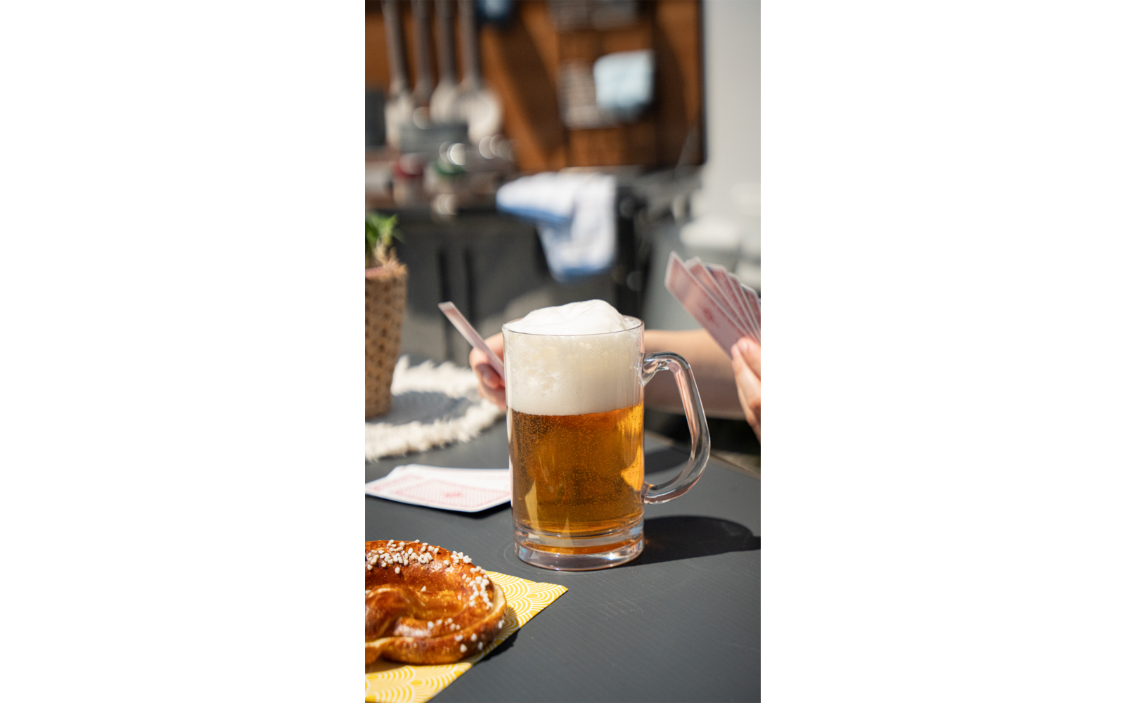Glas Bier mit Schaum auf einem Tisch, unscharfer Hintergrund mit Gästen