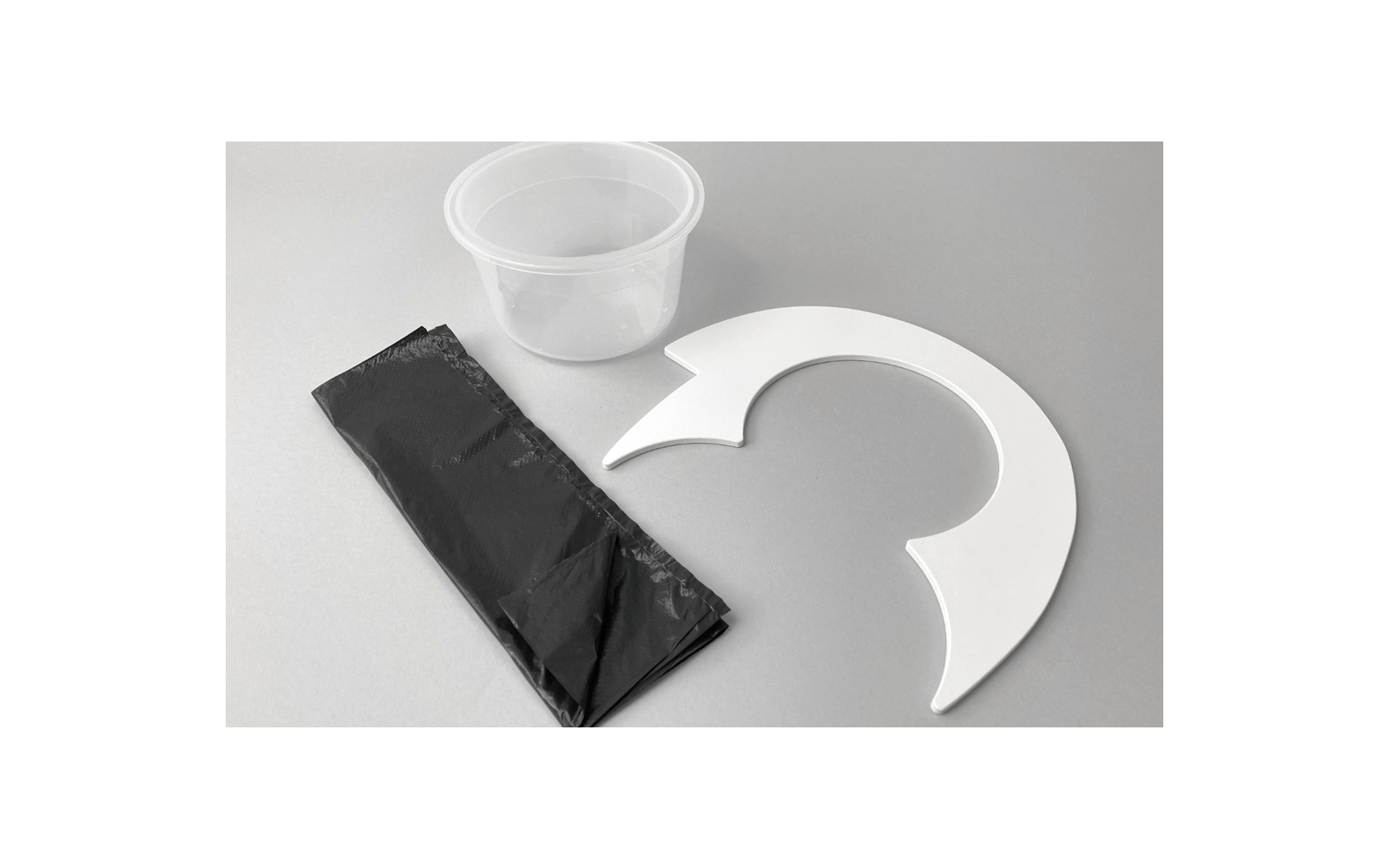 Gobelet en plastique, sac noir et feuille de papier ronde blanche avec découpes sur fond gris