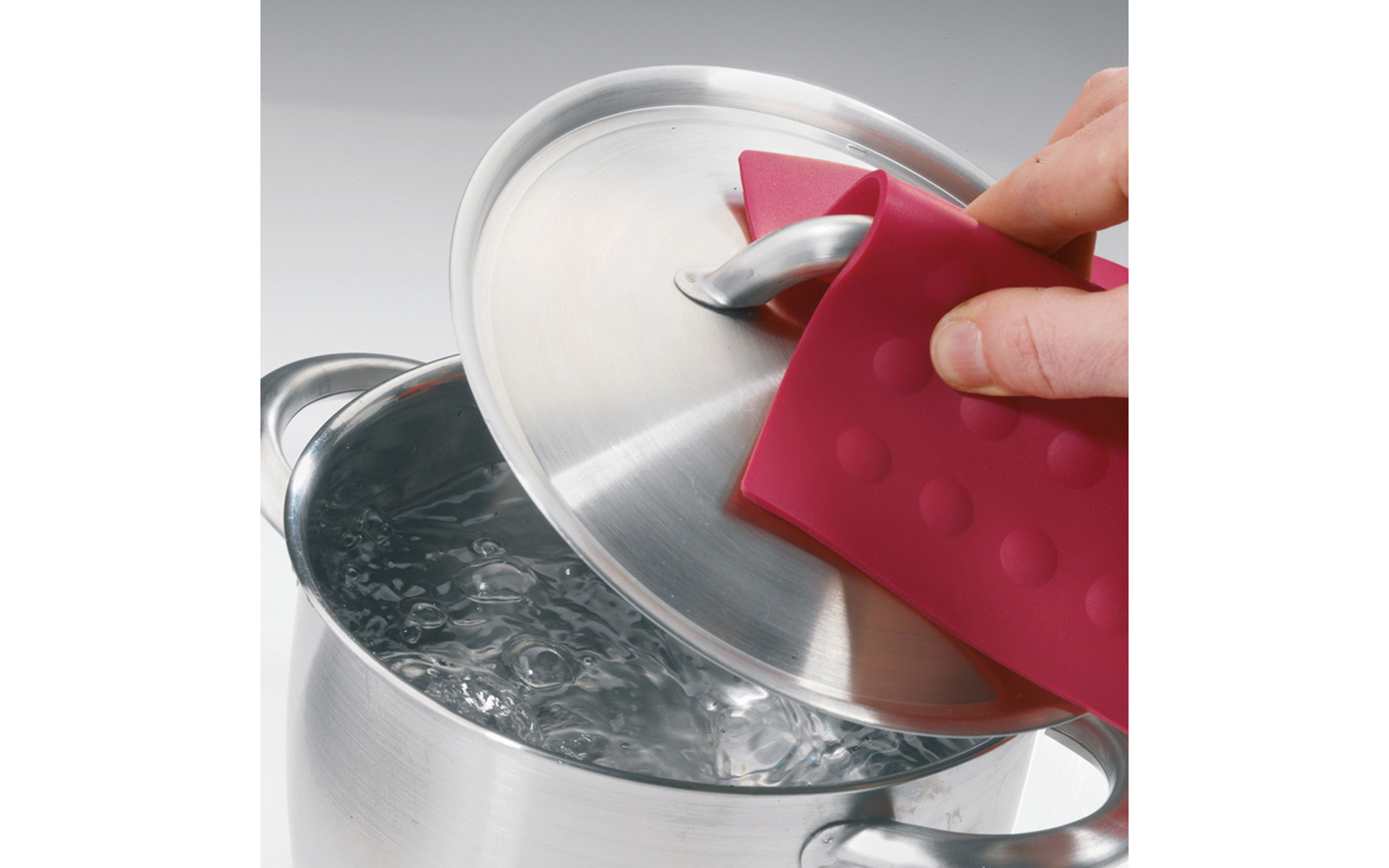 Hand mit rosa Silikon-Topflappen hebt einen Edelstahldeckel, darunter sprudelndes Wasser im Topf