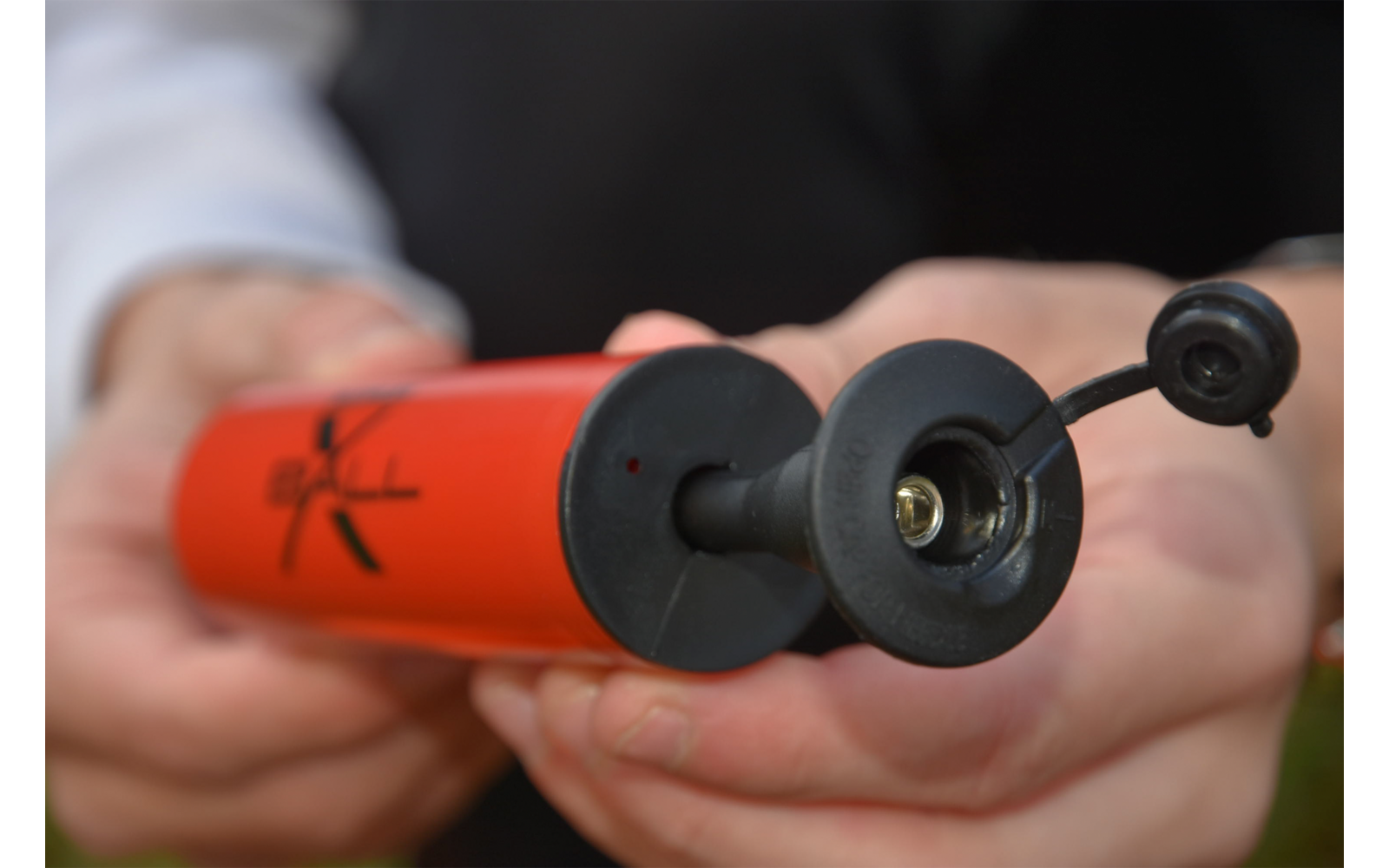 Hand hält eine rote Fahrradpumpe mit offenem Ventil