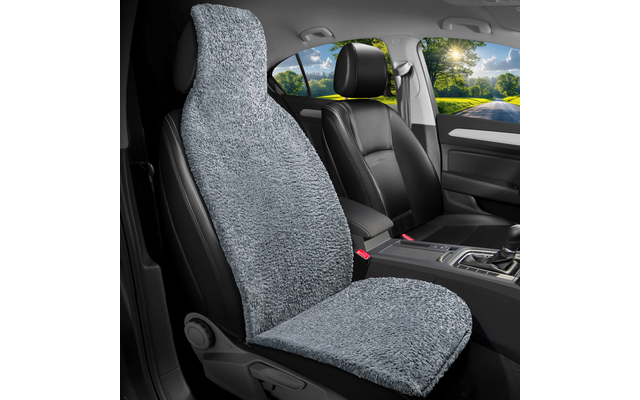 Autoinnenraum mit vorderem Sitz, bedeckt von grauem, flauschigem Sitzbezug; schwarzer vorderer Sitz, Mittelkonsole und Straße mit Bäumen durch die Fenster