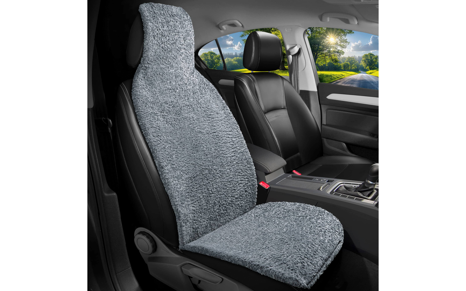 Autoinnenraum mit vorderem Sitz, bedeckt von grauem, flauschigem Sitzbezug; schwarzer vorderer Sitz, Mittelkonsole und Straße mit Bäumen durch die Fenster