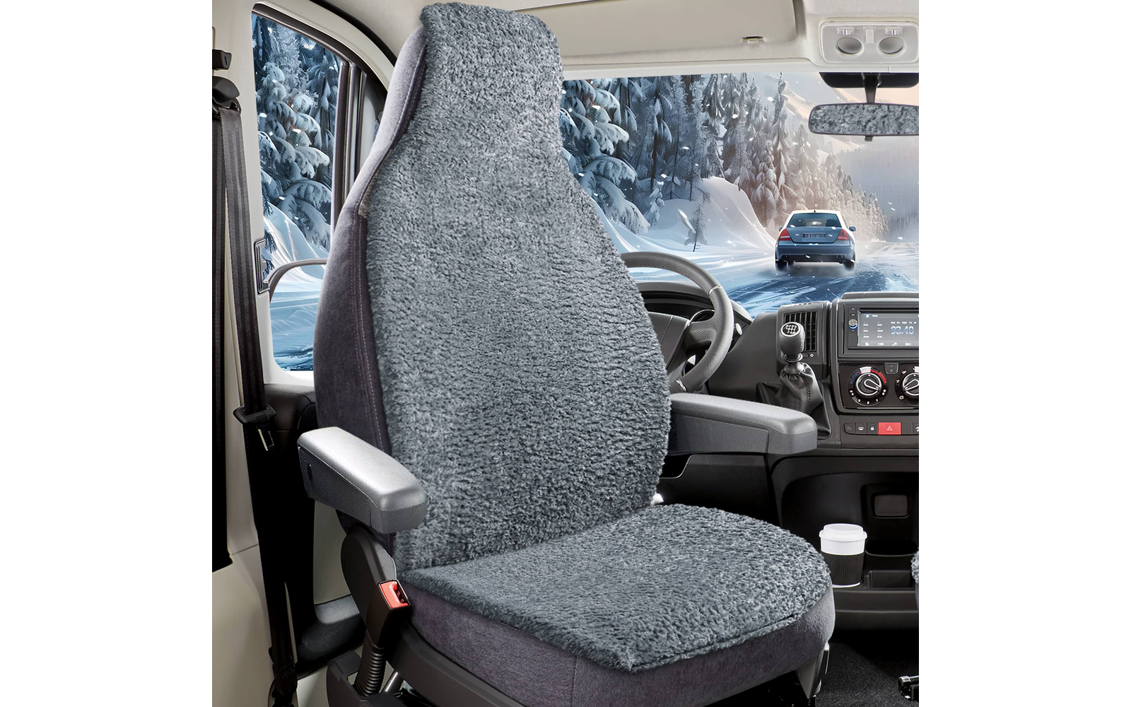 Fahrersitz mit grauem, flauschigem Sitzbezug, Lenkrad und Armaturenbrett; Pappbecher im Getränkehalter; durch die Windschutzscheibe schneebedeckte Bäume und ein fahrendes Auto auf einer verschneiten Straße