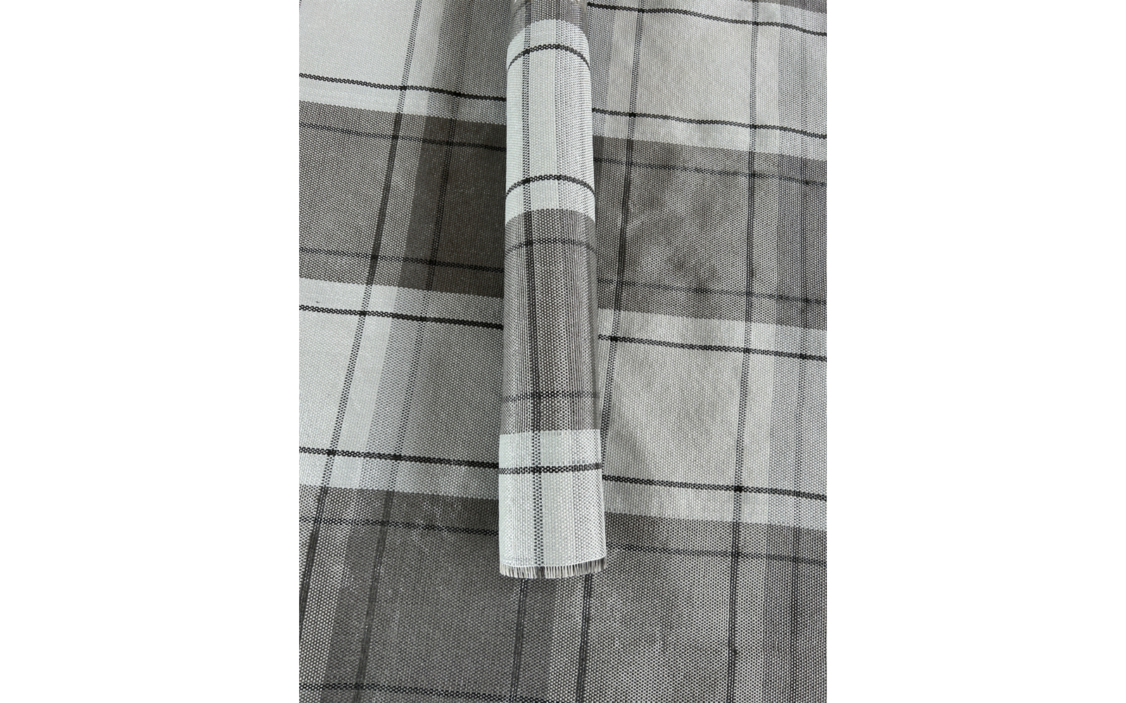 Rolle eines karierten grauen und weißen Stoffes auf einem karierten grauen und weißen Untergrund