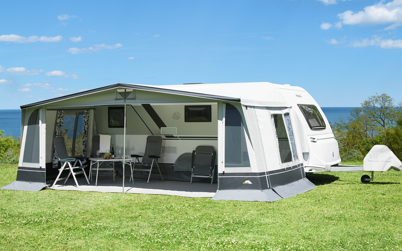 Caravan with awning on green grass under a blue sky