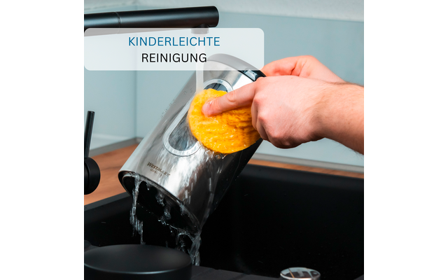 Hand with sponge cleaning a stainless steel kettle over a sink, water pouring from the spout; visible label reading 'KINDERLEICHTE REINIGUNG'