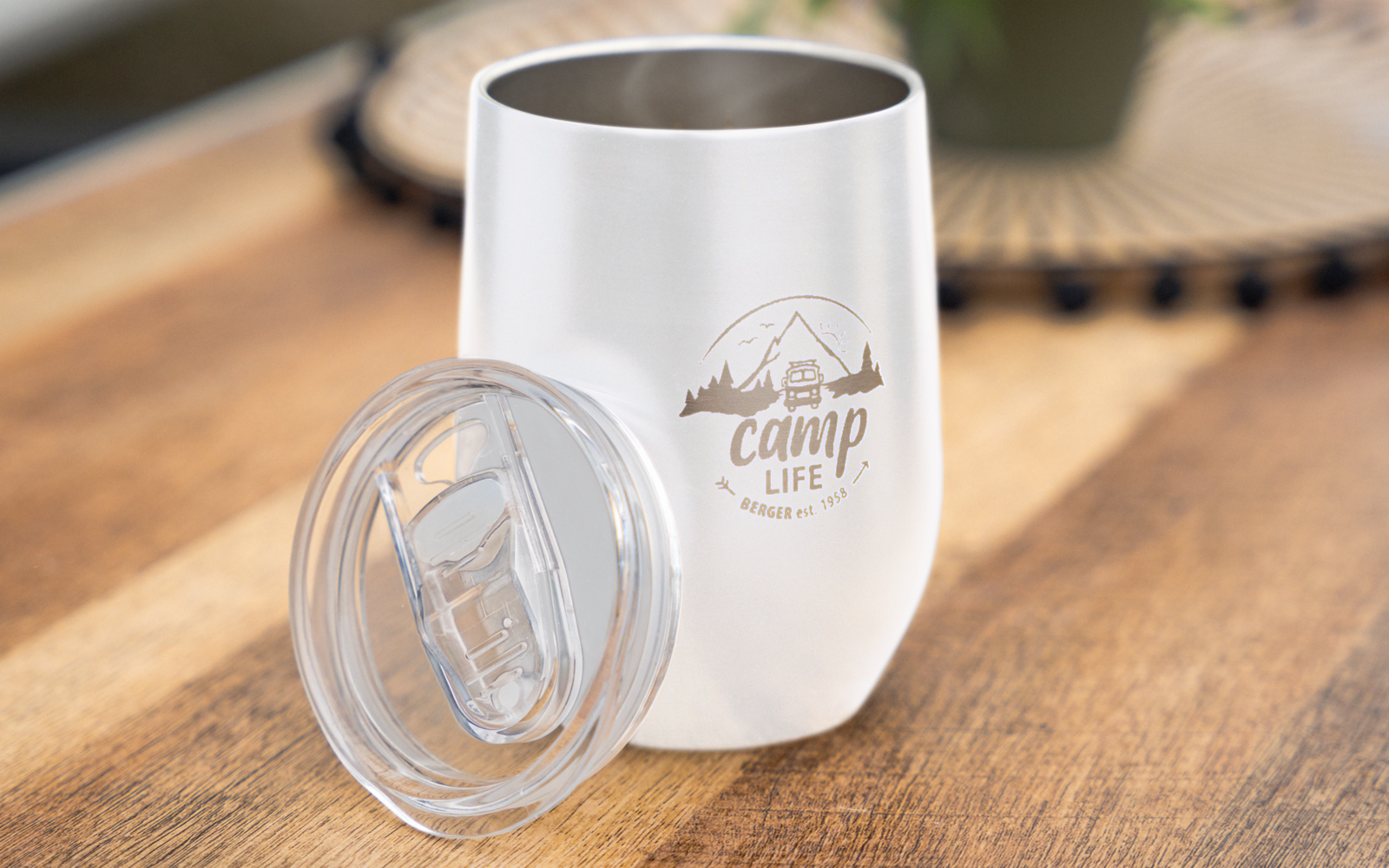Gobelet en acier inoxydable blanc avec couvercle sur table en bois, inscription 'Camp Life' et motif montagne