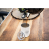 Koffie wordt uit een koffiepot in een wit kopje op een houten tafel gegoten