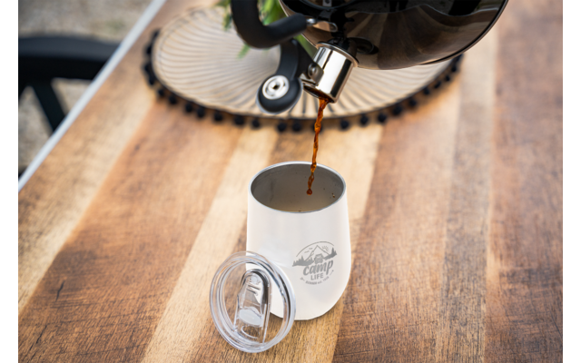 Koffie wordt uit een koffiepot in een wit kopje op een houten tafel gegoten