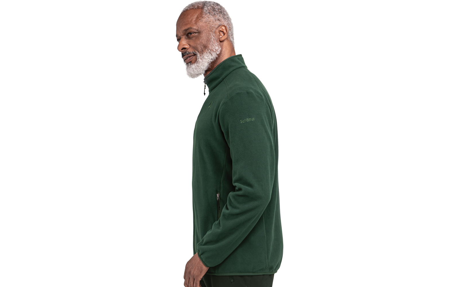 Seitliches Bild einer stehenden Person mit grauen Haaren und Bart, die einen dunkelgrünen Fleecepullover mit Reißverschluss trägt, vor weißem Hintergrund