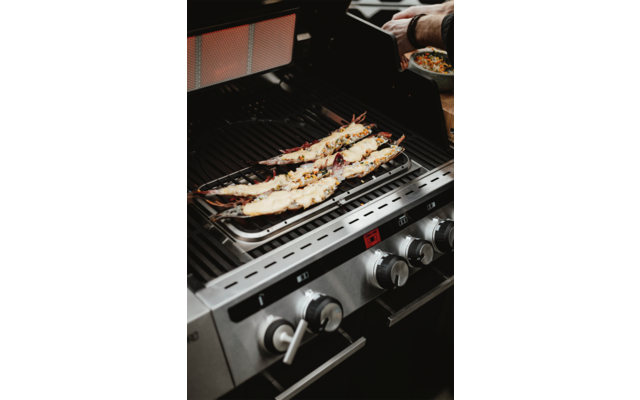 Fischstücke liegen auf einem Gasgrill und werden gegrillt