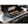 Ein Gasgrill mit mehreren Burger-Patties auf dem Rost und einer Hand, die eine Grillzange hält