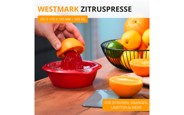 Main presse une orange coupée sur une presse à agrumes rouge sur un plan de travail en bois; orange coupée à côté, corbeille métallique avec oranges et citrons verts; mention "WESTMARK ZITRUSPRESSE" en haut