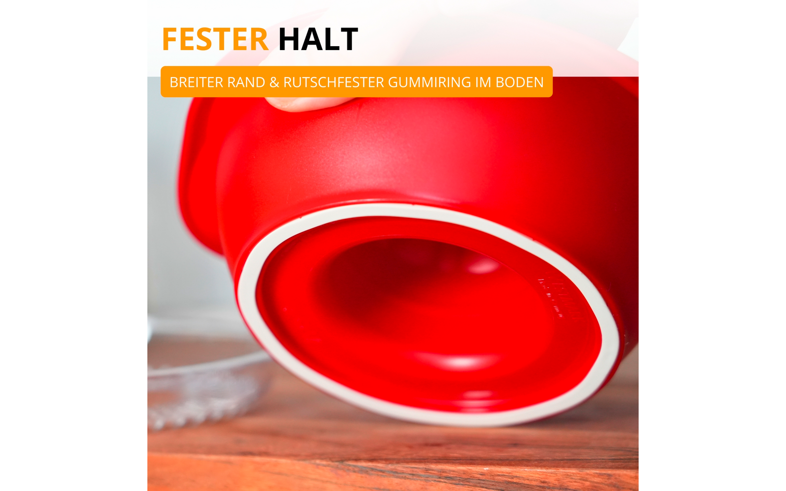 Gros plan d’un objet rond rouge avec un anneau en caoutchouc blanc au bord sur une surface en bois ; en haut à gauche, partie d’une bannière orange et blanche avec du texte