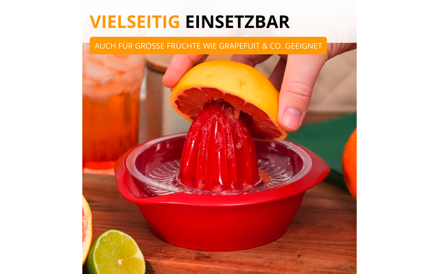 Main pressant un agrume coupé en deux à la pulpe rouge sur une presse à jus rouge ; le jus coule dans la coupelle, quartier de citron vert, orange et verre avec boisson sur une surface en bois en arrière‑plan