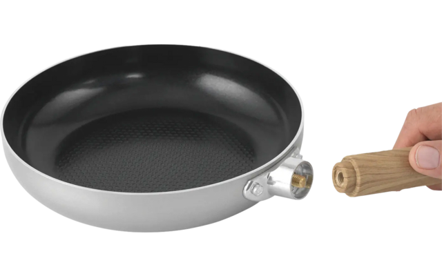 Hand houdt een spatel boven een grijze pan met houten handvat