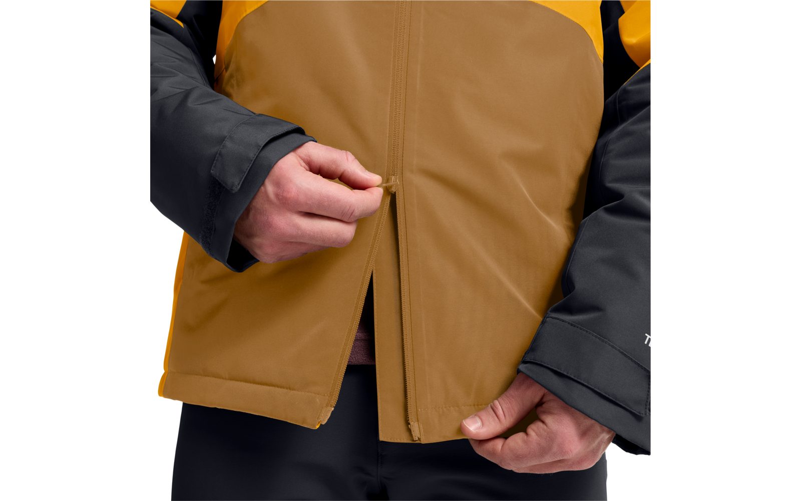 Hände, die an einem Reißverschluss einer zweifarbigen Jacke (braun und gelb) mit schwarzen Ärmeln ziehen