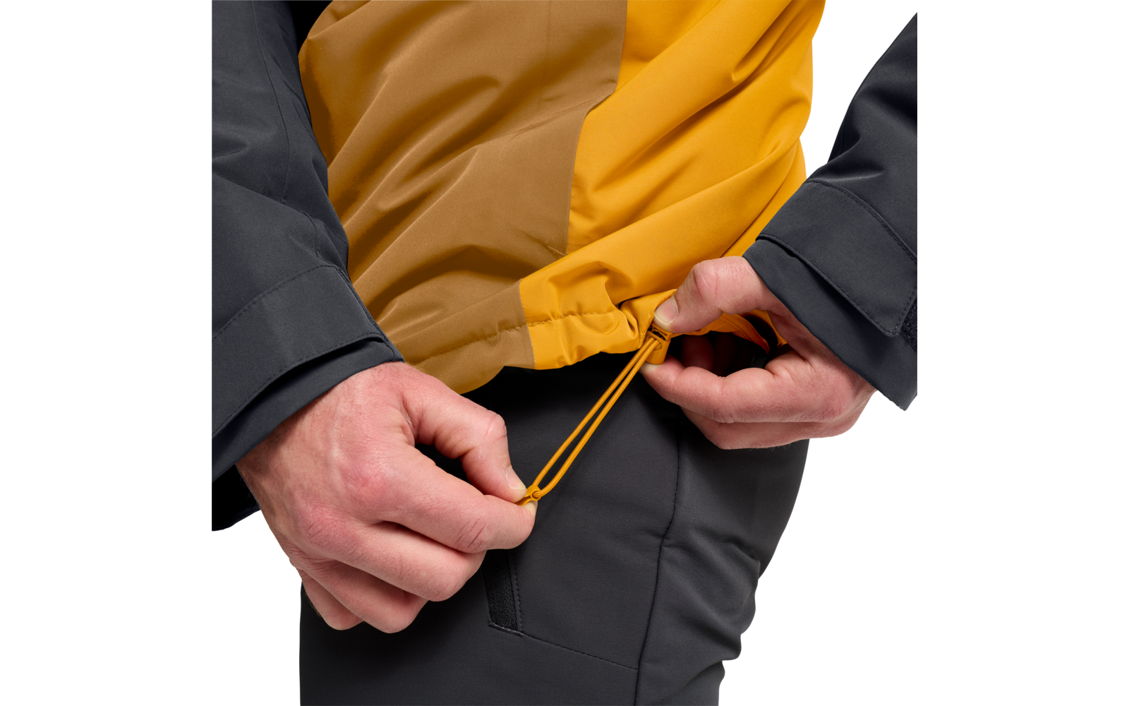 Zwei Hände ziehen an einem gelben Kordelzug am Saum einer zweifarbigen gelben Jacke; schwarze Ärmel und dunkle Hose sichtbar