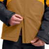 Hände, die an einem Reißverschluss einer zweifarbigen Jacke (braun und gelb) mit schwarzen Ärmeln ziehen