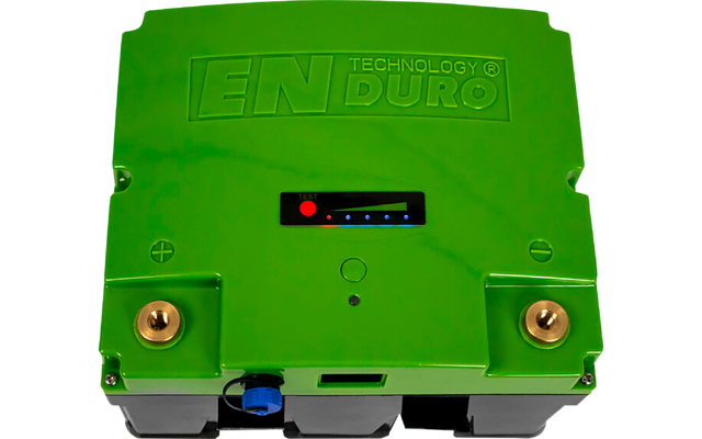 Grünes rechteckiges Elektronikgehäuse mit geprägtem Schriftzug 'EN TECHNOLOGY ENDURO', kleines mittiges Display mit rotem Punkt und blauen LEDs, zwei goldfarbene Metallanschlüsse, blauer Anschluss unten, weißer Hintergrund