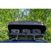 Box da tetto nero aperto sul tetto dell'auto con tre borse nere, portapacchi visibile, alberi sullo sfondo
