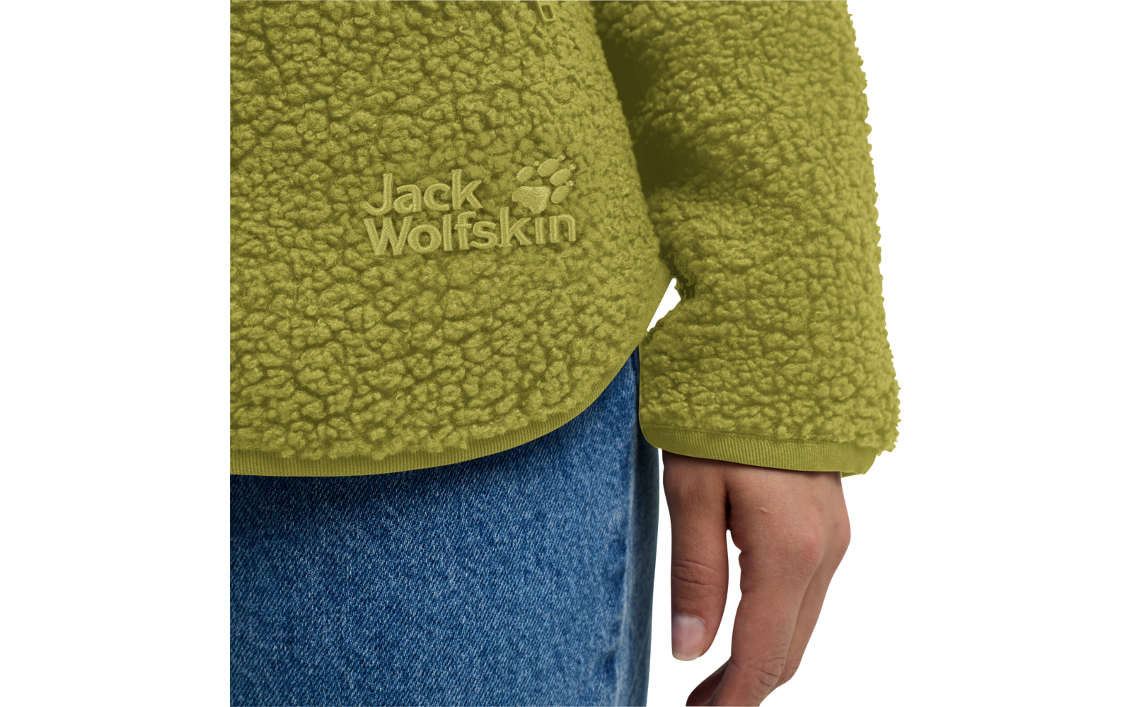 Groene teddyfleece met "Jack Wolfskin"-logo ter hoogte van de heup, rechterhand langs het lichaam, blauwe spijkerbroek