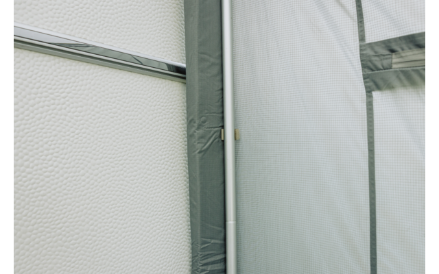 Texturierte weiße Fläche links, vertikale weiße Metallstange nahe der Bildmitte, graugrüne Stoffbespannung mit Nähten und dunklerem Rand rechts
