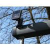 Solarlampe auf einem schwarzen Rohr mit Baumstämmen im Hintergrund
