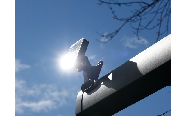 Satellitenschüssel vor blauem Himmel mit Sonne und Ästen