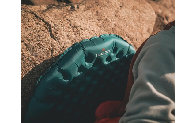 Een deel van een blauwe waterstoel en een mouw van een grijs kledingstuk op een stenen vloer