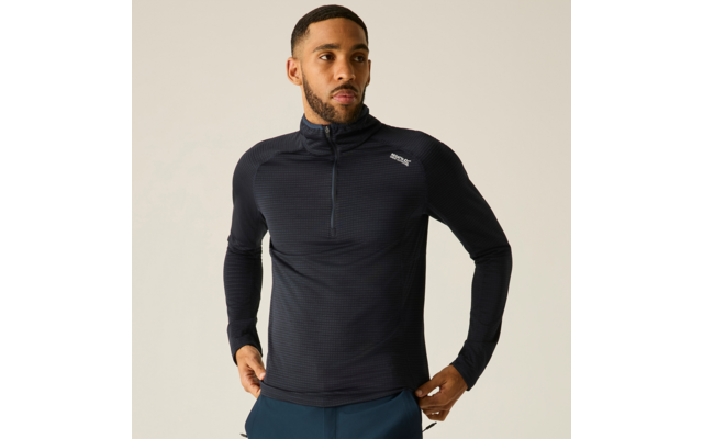 Homme portant un haut de sport bleu foncé à manches longues, zip court et petit logo blanc sur fond clair