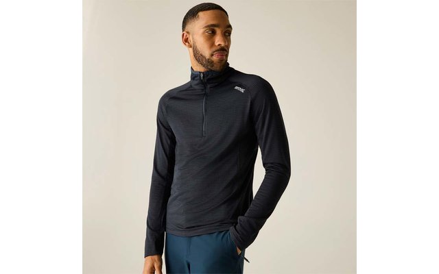 Personne portant un haut noir à manches longues avec une fermeture éclair courte et petit logo blanc sur la poitrine, pantalon bleu, debout sur fond clair et regardant vers la droite