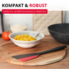 Spatule noire avec tête rouge sur une planche à découper ronde en bois ; en arrière-plan un bol de riz jaune avec une cuillère, une poêle noire, une tomate, un bol de céréales et un manique beige ; en haut à gauche des bandeaux de texte 'KOMPAKT & ROBUST' et 'HANDLICH, WIDERSTANDSFÄHIG & PRAKTISCH'