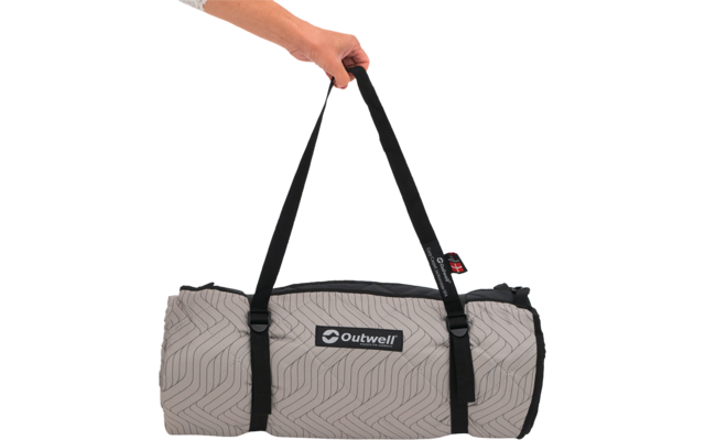 Hand, die schwarze Tragegurte einer hellgrauen, gemusterten, zusammengerollten Outwell-Matte hält